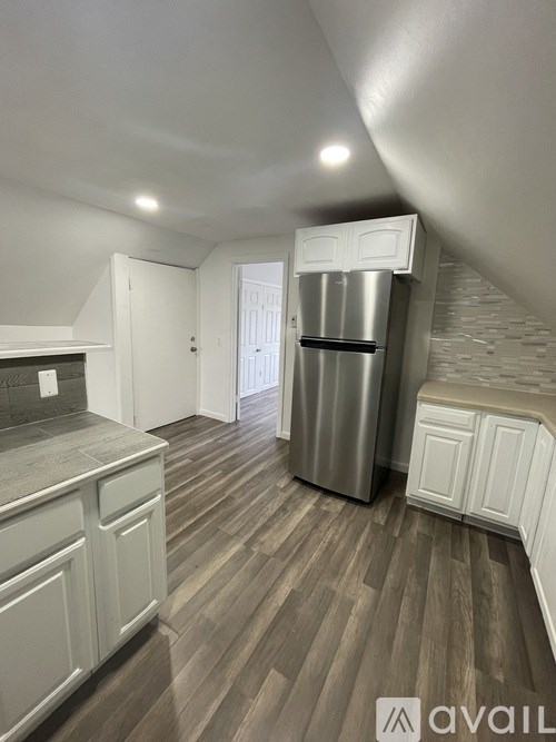 A kitchen with a refrigerator and wooden floors.
