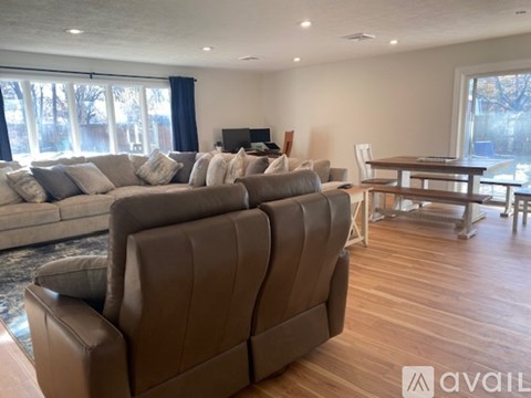 A living room with a brown leather couch and a wooden dining table.