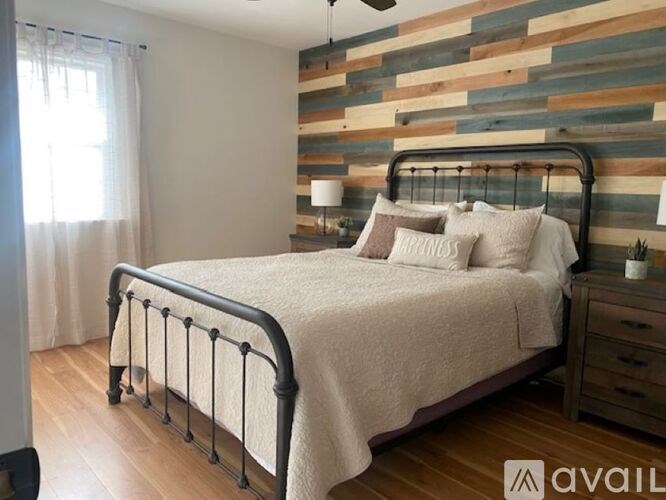 A bedroom with a bed, nightstand, and a wooden wall.