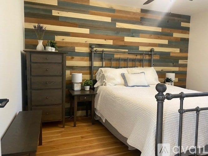 A bedroom with a bed, nightstand, and wooden wall paneling.