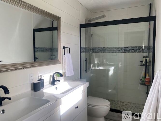 A white sink with a mirror above it and a toilet behind it.