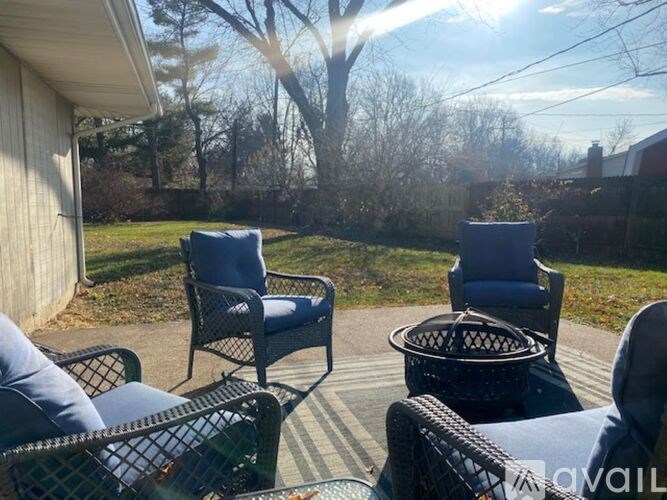 A sunny day in a backyard with two chairs and a table.