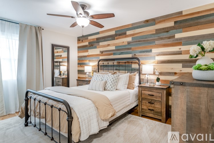 A living room with a white couch, a chair, and a table with a vase of flowers on it.