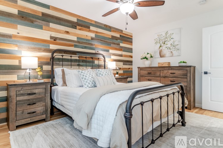 A bedroom with a bed, nightstand, and a wooden wall panel.