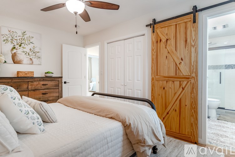 A bedroom with a bed, a ceiling fan, and a wooden door.