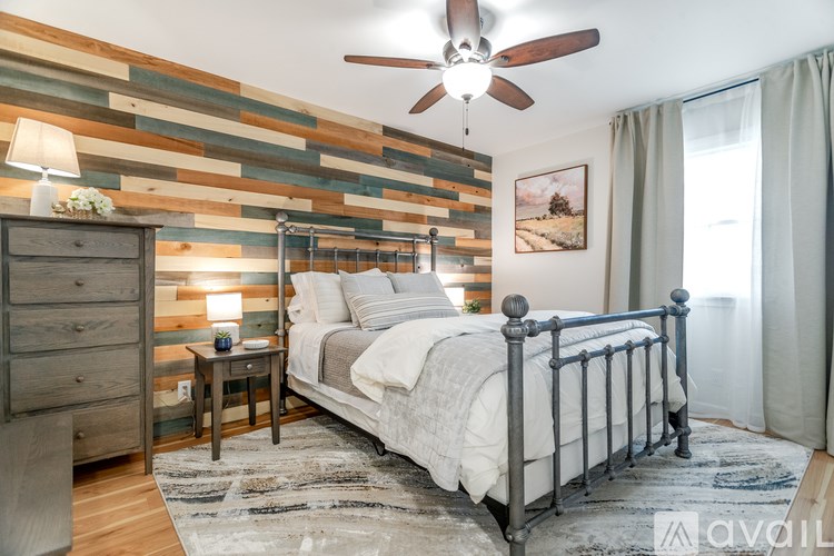 A bedroom with a bed, nightstand, and a wooden wall panel.