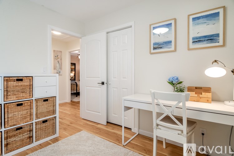 A room with a desk, chair, and two pictures on the wall.