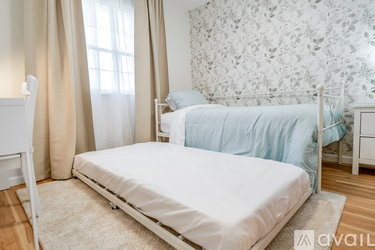A bedroom with a white bed and a floral wallpaper.