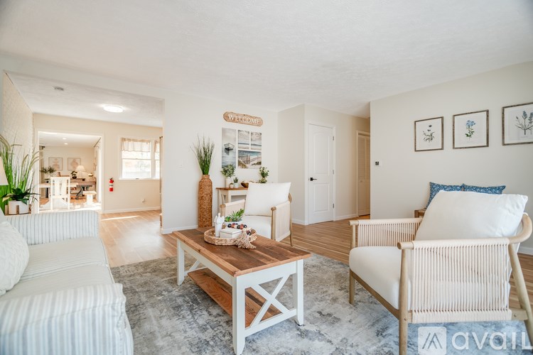 A living room with a white couch, a wooden coffee table, and a white chair.
