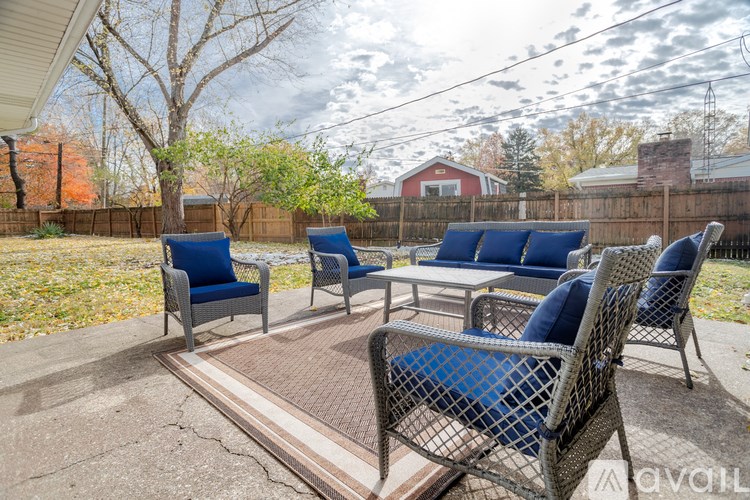 A patio with blue cushioned chairs and a table.