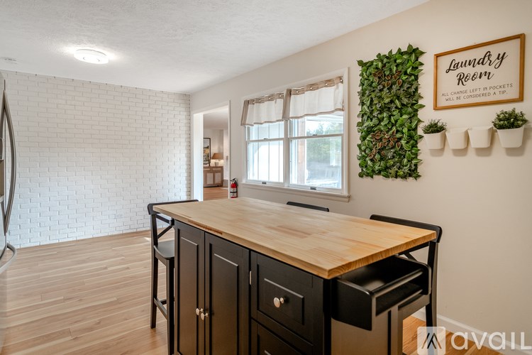 A living room with a grey couch, a grey armchair, a white table, and pictures on the wall.