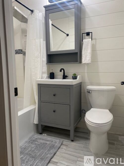 A bathroom with a toilet, sink, and mirror.