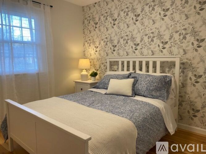 A bedroom with a white bed and a floral wallpaper.