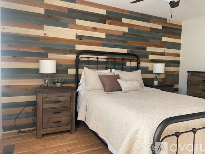 A bedroom with a bed, nightstand, and a wooden wall.