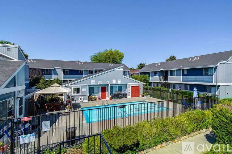 A pool surrounded by a black fence and a building with a red door.