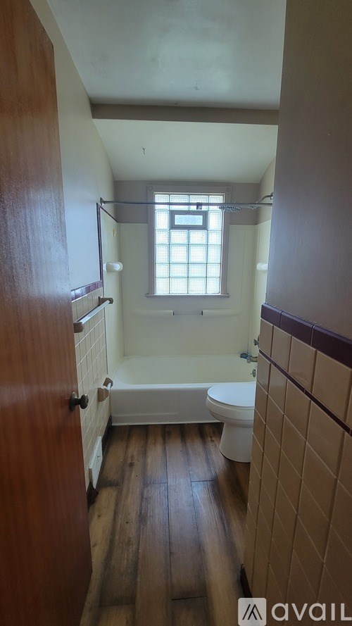 A small bathroom with a toilet, tub and window.