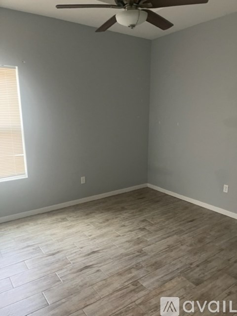 A room with a ceiling fan and wooden flooring.