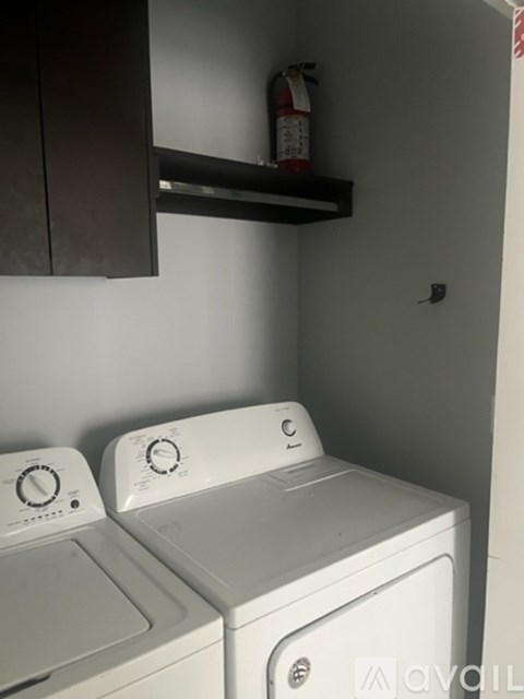 Two white front loading washing machines in a small laundry room.