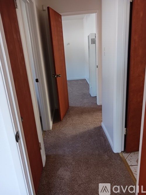 A hallway with carpeted floor and white walls.