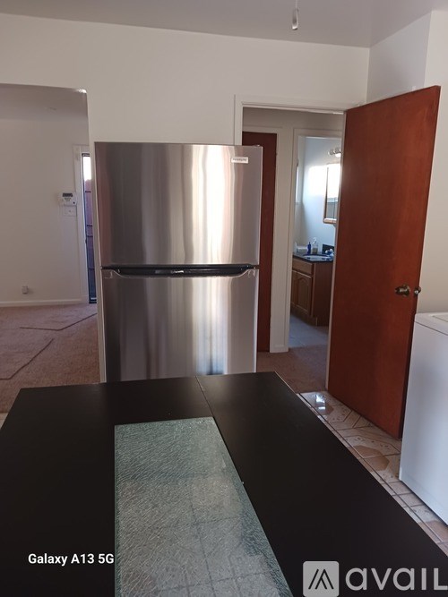 A kitchen with a stainless steel refrigerator and a black countertop.