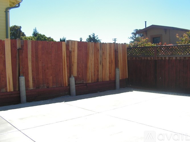 A wooden fence with a white tiled floor in front of a house.