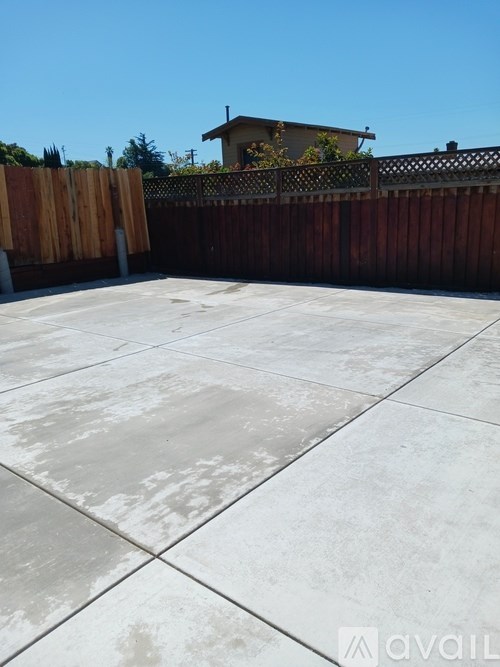 A patio with a tiled surface and a wooden fence.