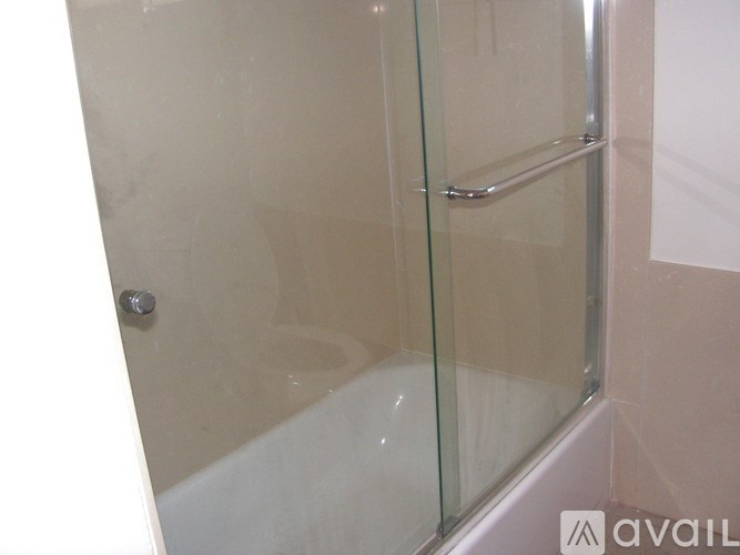 A glass shower door with a silver handle.