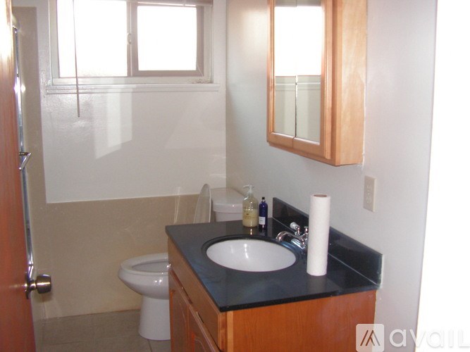 A bathroom with a toilet, sink, mirror and a door.