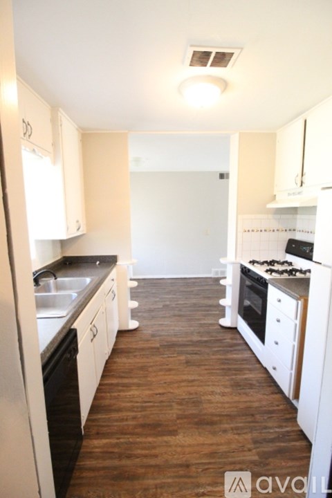 A kitchen with white cabinets and a wooden floor.