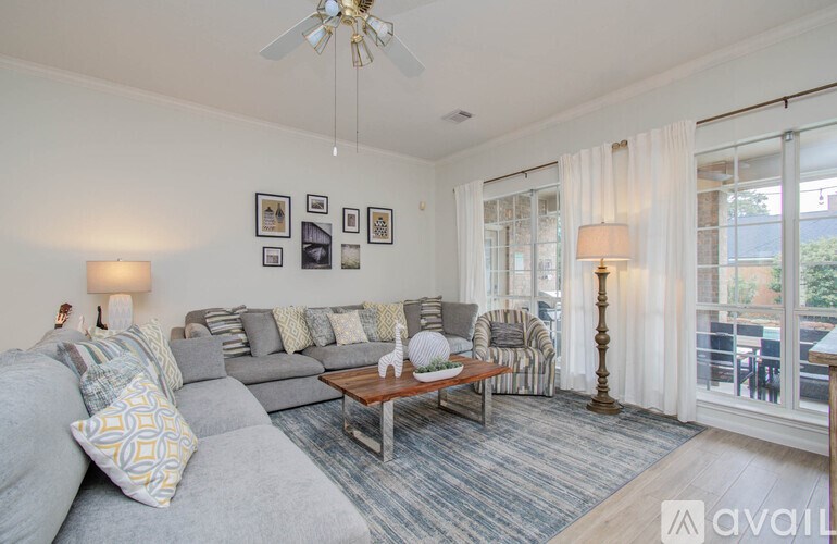 A living room with a grey couch, a coffee table, and a ceiling fan.
