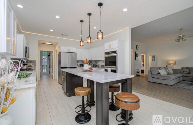 A modern kitchen with a bar stool and pendant lights.