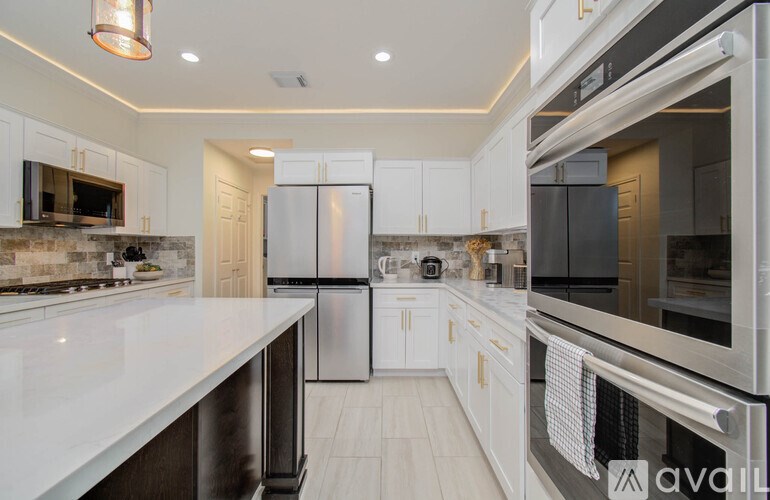 A modern kitchen with white cabinets and stainless steel appliances.