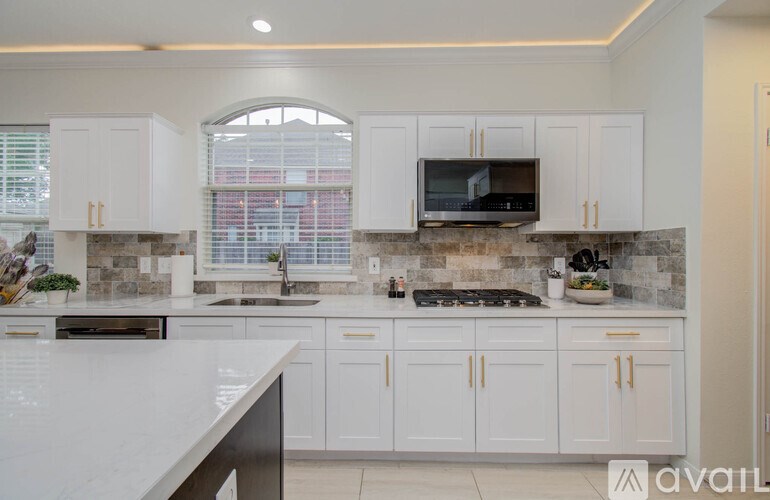 A kitchen with white cabinets and a stone backsplash.