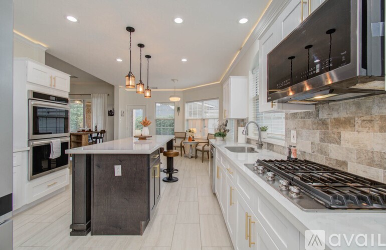 A modern kitchen with a dark island and stainless steel appliances.