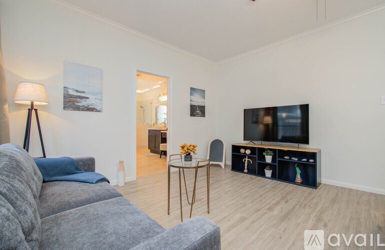 A living room with a grey couch, a wooden table, and a television.