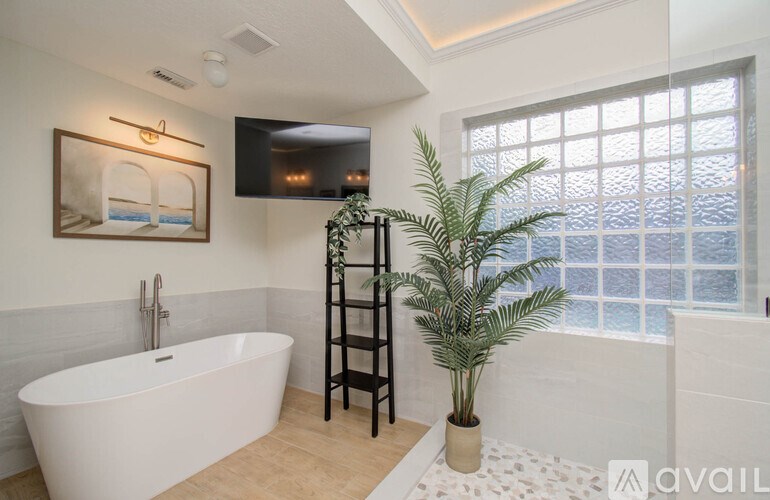 A bathroom with a white tub and a plant.