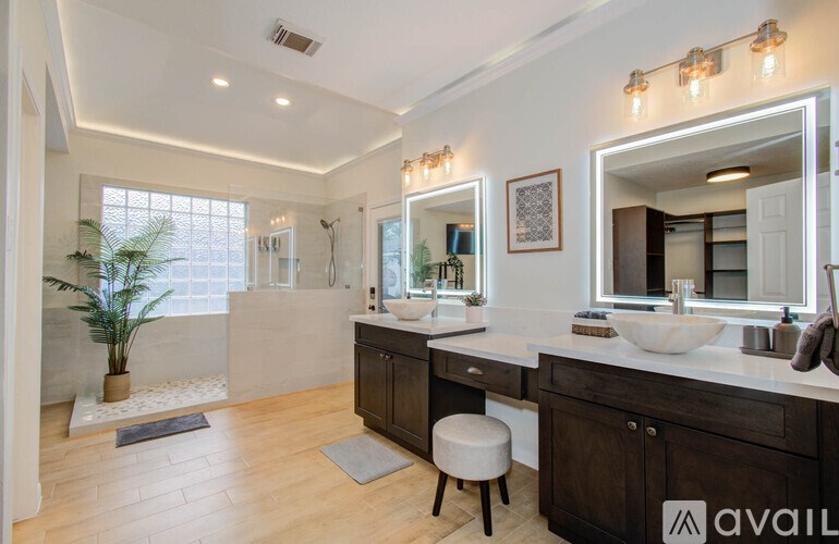 A bathroom with a vanity, a mirror, and a potted plant.