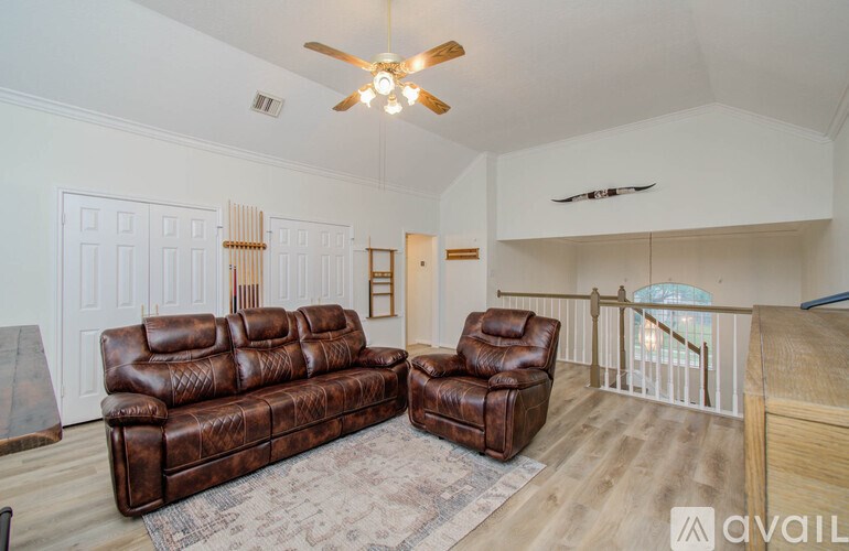 A living room with a brown leather couch and chair.