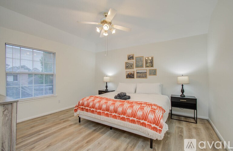 A bedroom with a bed, two lamps, and pictures on the wall.