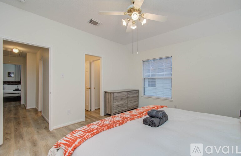 A bedroom with a bed, dresser, and ceiling fan.