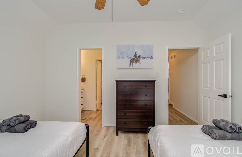 A bedroom with two beds and a painting of a horse on the wall.