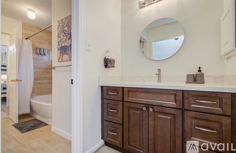 A bathroom with a wooden vanity and a round mirror.