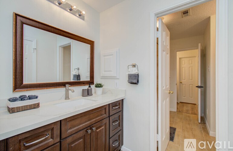 A bathroom with a white counter top and brown cabinets.