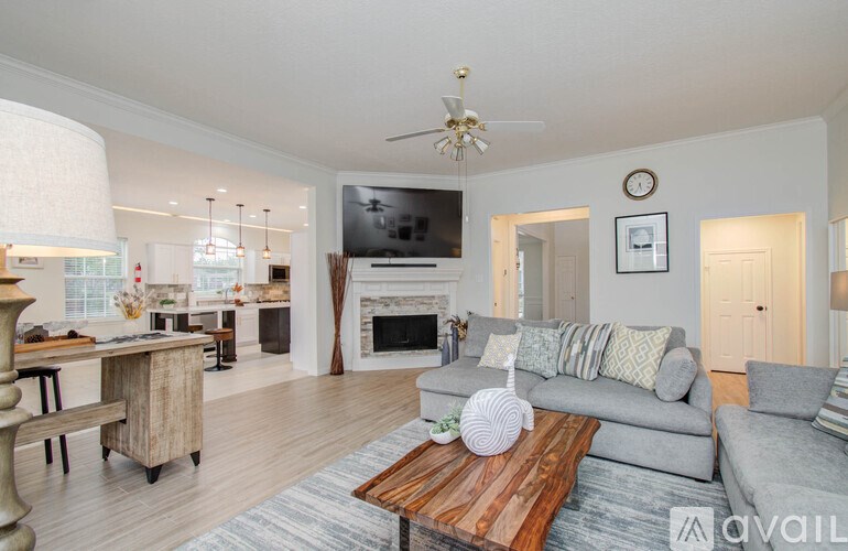 A living room with a fireplace and a grey couch.