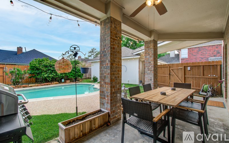A patio with a table and chairs overlooking a pool.