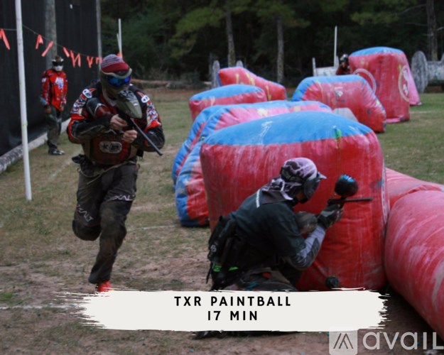 A man in a red and black outfit is running through a course with blue and red inflatable obstacles.