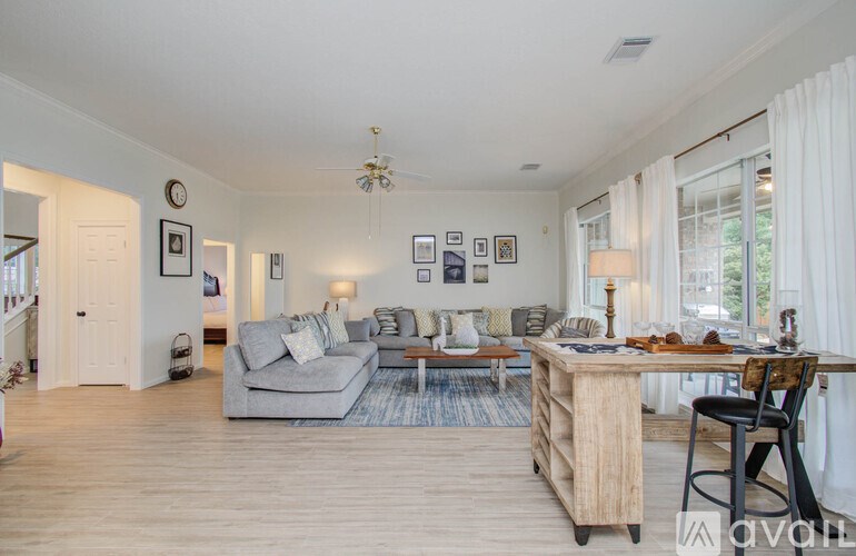 A living room with a grey couch, a wooden table, and a white chair.