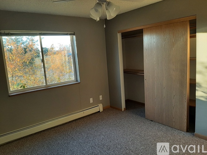 A room with a ceiling fan and a large window.