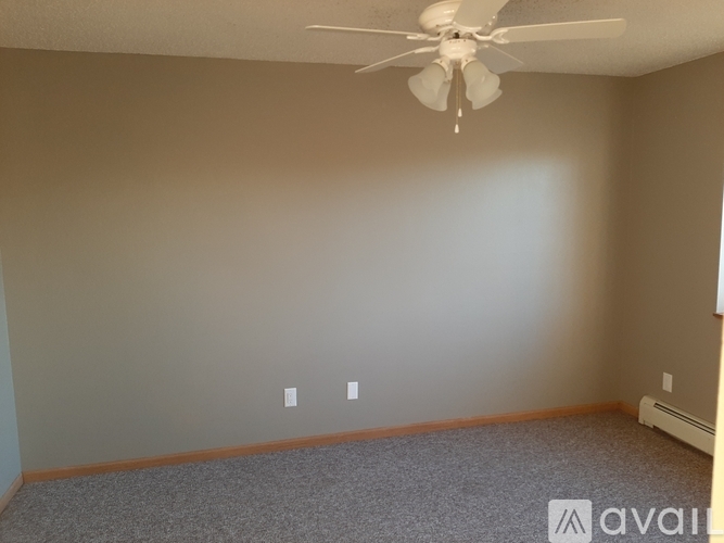 A room with a ceiling fan and carpeted floor.