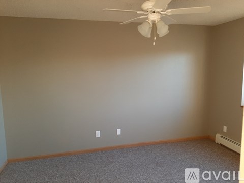 A room with a ceiling fan and carpeted floor.